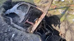 السيارة تبرز من حفرة في الحديقة