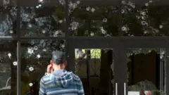 Hombre frente a ventana con balazos