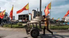 መቀለ ከተማ የትግራይ ክልል እና የኢትዮጵያ ባንዲራ በተሰቀለበት አደባባይ በኩል ጋሪ የሚገፋ ወጣት