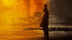 Мужчина стоит на фоне моря и атомной электростанции