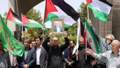 Un homme soulevant la photo d'Ismail Haniyeh au milieu des gens