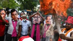 Sri Lanka's main opposition activists wearing masks of Sri Lanka's President Gotabaya Rajapaksa (C), Sri Lanka's Prime Minister Mahinda Rajapaksa (2R) and Basil Rajapaksa (L) take part with others in a protest against rising living costs, at the entrance of the president's office in Colombo on March 15, 2022.