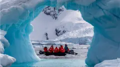 Tourists exploring an iceberg arch in Cierva Cove along the west coast of Graham Land, Antarctic Peninsula, Antarctica