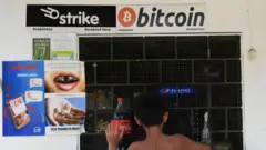 un niño hace unas compras por una ventana en El Salvador. sobre la ventana hay un letrero que dice bitcoin.