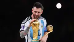 ليونيل ميسي يحمل جائزة أفضل لاعب في مونديال 2022، ويضع يده على كأس العالم