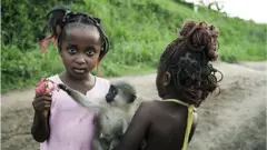Deux filles qui jouent avec un petit singe