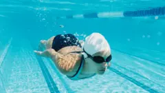 Mulher nadando em piscina debaixo d'água