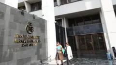 Merkez Bankası logosunun önünde yürüyen iki kadın