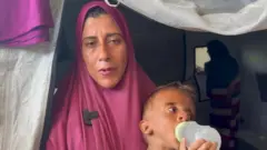 Hedaya al-Muta'wi com seu filho chupando uma mamadeira vazia