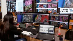 Controladores de tráfego aéreo observam telas de controle durante uma apresentação à imprensa como parte de um teste da Iniciativa Nacional de Drones no Centro de Controle Aéreo de Drones, na cidade costeira israelense de Tel Aviv, em 11 de outubro de 2021