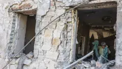 Una mujer mayor camina en su casa, gravemente dañada por un ataque ruso en la ciudad de Druzhkivka, Ucrania.