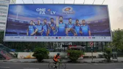 In this picture taken on October 10, 2020, a cyclist rides past a hoarding of Mumbai Indians cricketers of the Indian Premier League (IPL) cricket tournament in Mumbai.