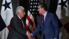 O secretário de Defesa dos Estados Unidos, Pete Hegseth, cumprimenta o presidente do Panamá, José Raúl Mulino, em frente às bandeiras dos dois países