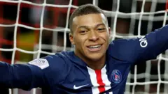 Kylian Mbappe, in close-up, turning and smiling to celebrate a goal