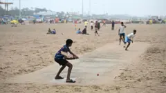 Crianças jogando críquete na praia, na Índia