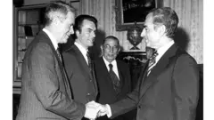 محمدرضا شاه در حال فشردن دست سایروس ونس وزیر خارجه آمریکا. دیوید اوئن در کنار او ایستاده است