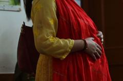 Mulher com trajes indianos e grávida coloca a mão na barriga