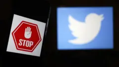 Un panneau stop à côté du logo Twitter