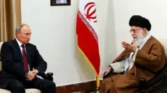 O presidente russo, Vladimir Putin, de terno preto e gravata vermelha, conversando sentado com o ex-líder supremo do Irã, o aiatolá Ali Khamenei, à sua direita, com a bandeira iraniana ao fundo entre os dois
