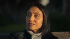 Uma mulher com cabelo castanho e olhos castanhos olha para longe da câmera