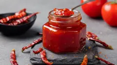 Банка красного джема с перцем чили на переднем плане