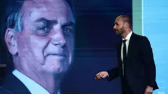 Eduardo Bolsonaro em frente a uma foto do pai, Jair Bolsonaro.