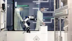 Bir laboratuvarda çalışan tulum giymiş bilim insanları.