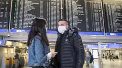 Gente en aeropuerto con tapaboca.