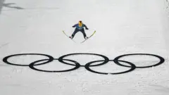 Alman milli kayakçı Katharina Schmid'in kayakla atlayış antrenmanında atlayış sırasında çekilmiş bir fotoğrafı, karın üstünde olimpiyat halkaları var. 