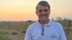Luís Fernando Laranja Fonseca sorrindo em pasto, com sol se pondo ao fundo