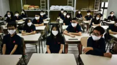 Students wearing face masks sit inside a classroom at the Marie Curie school in Hanoi on May 4, 2020