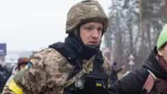 A Ukrainian soldier helps a civilian woman in Kyiv