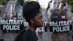 Black woman in front of police in riot gear
