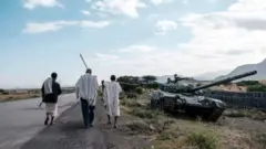 ብጥቓ ዝዓነወት ታንኪ ዝሓልፉ ዘለዉ ሰለስተ ሰብኡት