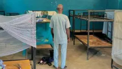 A man stands with his back to the camera in a dormitory at St. Mary's Boarding School, in Babiri village, Niger State, Nigeria