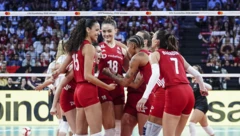 Türkiye formalı voleybolcular file önünde toplu halde sevinç yaşıyor. Arkada dolu tribünler görünüyor.