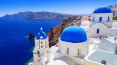 The town of Oia in Santorini, with white buildings and vibrant blue dome roofs and an amazing blue ocean