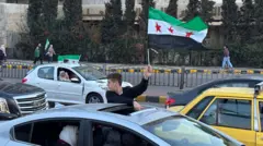 يرفع طفل سوري علم سوريا الجديد خلال خروجه من نافذة إحدى السيارات.
