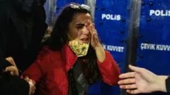 በፖሊስ ፊት አይኗን እያሸች ያለች ግለሰብ