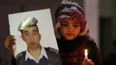 فتاة أردنية تحمل صورة للطيار معاذ الكساسبة وشمعة