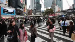 高層ビルに囲まれたスクランブル交差点を、大勢の人が行き交っている