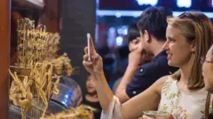 women taking photo to strange food