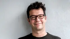 Nebojša Slijepčević sa naočalama, tamne kose i u sivoj majici gleda u kameru