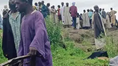 Villagers crowd one rocky green terrain for di landslide site for Darfur.