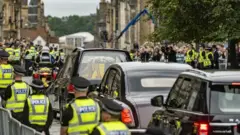 এডিনবরার রয়্যাল মাইল ধরে রানির কফিন নিয়ে শোকযাত্রার সময় নিরাপত্তার জন্য দুই পাশে পুলিশ মোতায়েন করা হয়