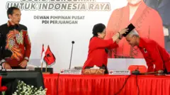 Ketua Umum PDI Perjuangan Megawati Soekarnoputri (tengah) menyematkan peci kepada calon Presiden 2024 yang diajukan PDI Perjuangan Ganjar Pranowo (kanan) disaksikan Presiden Joko Widodo (kiri) di Istana Batu Tulis, Bogor, Jawa Barat, Jumat (21/04).