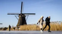 Skaters on the ice pass the windmills in Kinderdijk, The Netherlands, 13 February 2021.