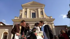 Parejas se besan frente a una iglesia de Terni