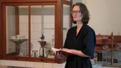 Sophie Hardock está parada en medio del laboratorio, con un cuaderno de gran tamaño en las tardes