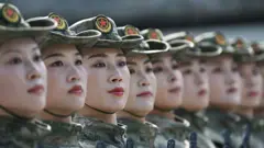 Mulheres do exército chinês uniformizadas olham na mesma direção com expressão séria